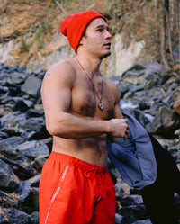 Man stood in front of rocks wearing Red dryrobe® Eco beanie 