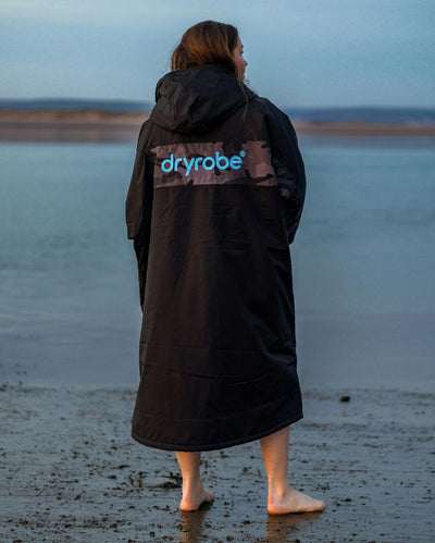 Adult female on beach wearing black blue remix Dryrobe®