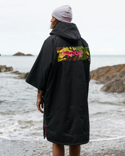 Adult male on beach wearing Dryrobe® Black pink camo remix
