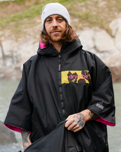 Adult male on beach wearing Dryrobe® Black pink camo remix