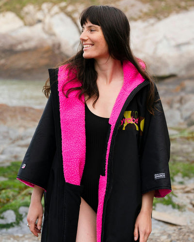 Adult female on beach wearing Dryrobe® Black pink camo remix