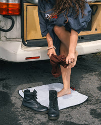 Woman next to a van standing on dryrobe® Change Mat while getting changed