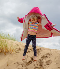 Child playing on sand dunes with a pink and beige Dryrobe®