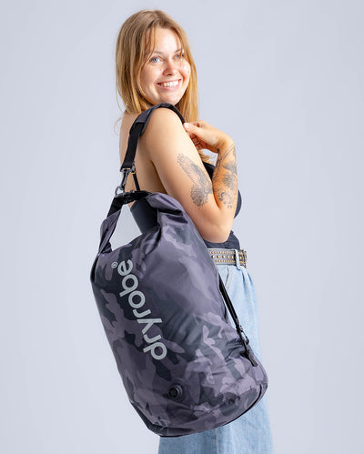 Woman in studio carrying black camo Dryrobe® compression bag 