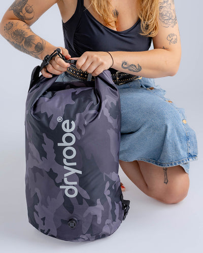 Woman in studio zipping up black camo Dryrobe® compression bag 