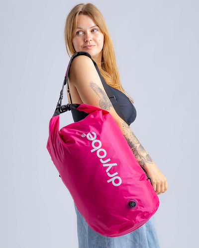 Woman in studio carrying hot pink Dryrobe® compression bag 