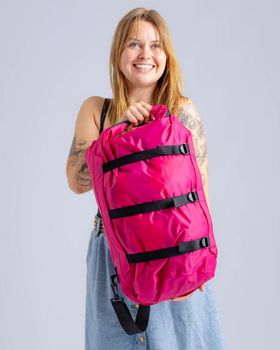 Woman in studio carrying hot pink Dryrobe® compression bag 