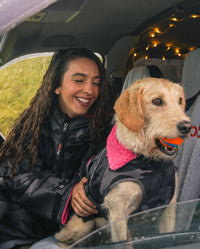 Woman sat in van next to a labradoodle, wearing Black Camo Pink dryrobe® Dog