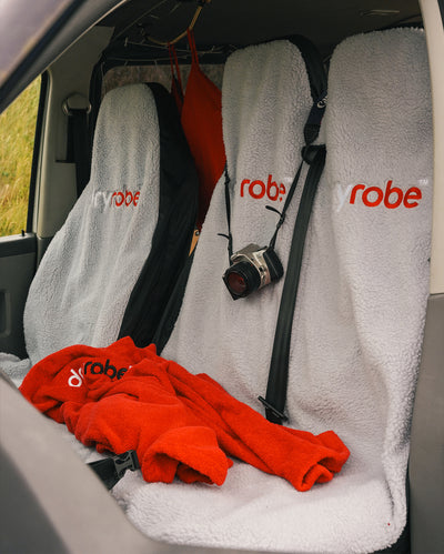 Single and Double dryrobe Car Seat covers in grey shown in van, with Red dyrobe Towel robe on top of seats, and camera hanging from headrest 
