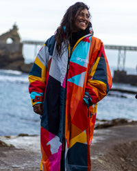 Woman stood smiling on beach, wearing dryrobe Advance Abstract 