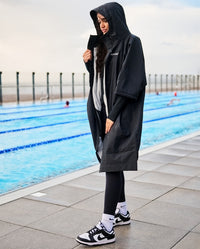 Woman stood next to a pool, wearing dryrobe® Lite