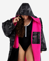 Woman looking down wearing Black Camo Pink dryrobe® Advance Long Sleeve with hood up