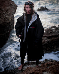 Person stood on rocks by the sea, wearing snorkel, wetsuit and Black Grey  dryrobe® Advance Long Sleeve