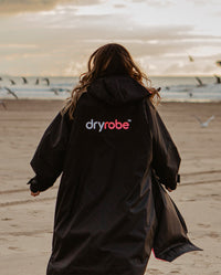 Woman running on beach, wearing Black Pink dryrobe® Advance Long Sleeve