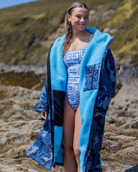 Woman on a beach wearing dryrobe Advance Long Sleeve changing robe in Blue Camo Blue, unzipped