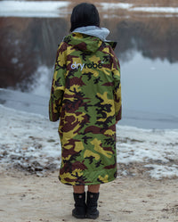 Woman stood in front of lake, facing away from camera, wearing Camo Grey dryrobe® Advance Long Sleeve
