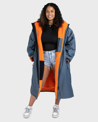 Person wearing a long grey and orange Dryrobe on a white background