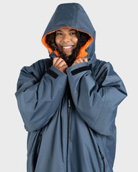 Person wearing a grey Dryrobe with an orange hood on a white background