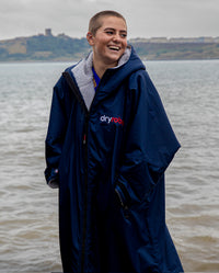 Woman stood in front of the sea, wearing  Navy Grey dryrobe® Advance Long Sleeve