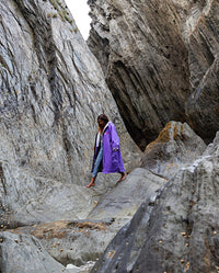 Woman walking across rocks on a beach, wearing Purple Grey dryrobe® Advance Long Sleeve 