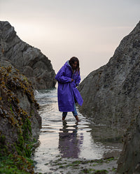 Woman walking through rock pool wearing Purple Grey dryrobe® Advance Long Sleeve 