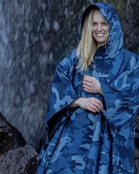 Close up of woman smiling in front of waterfall, wearing  Blue Camo dryrobe® Waterproof Poncho 