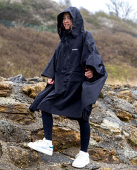 Girl stood on a rock, wearing Black Kids dryrobe® Waterproof Poncho
