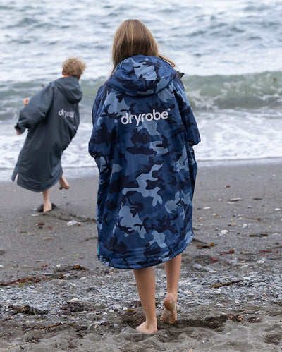 Kids playing by the sea on a beach, wearing Girl wearing dryrobe Advance Long Sleeve Changing robes