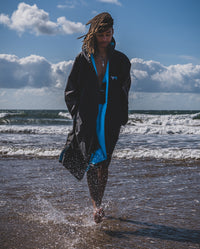 *MALE* walking out of the sea, wearing Black Blue dryrobe® Advance Long Sleeve