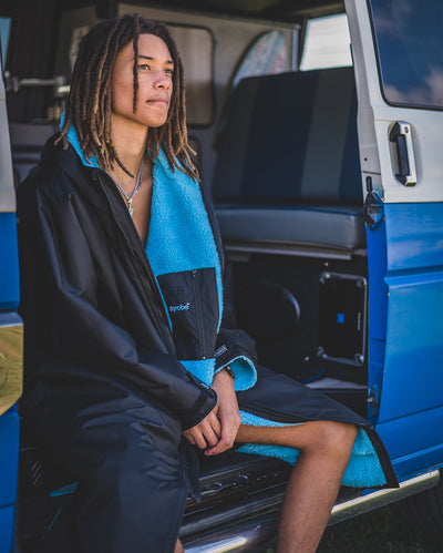 *MALE* sitting in a van, wearing Black Blue dryrobe® Advance Long Sleeve