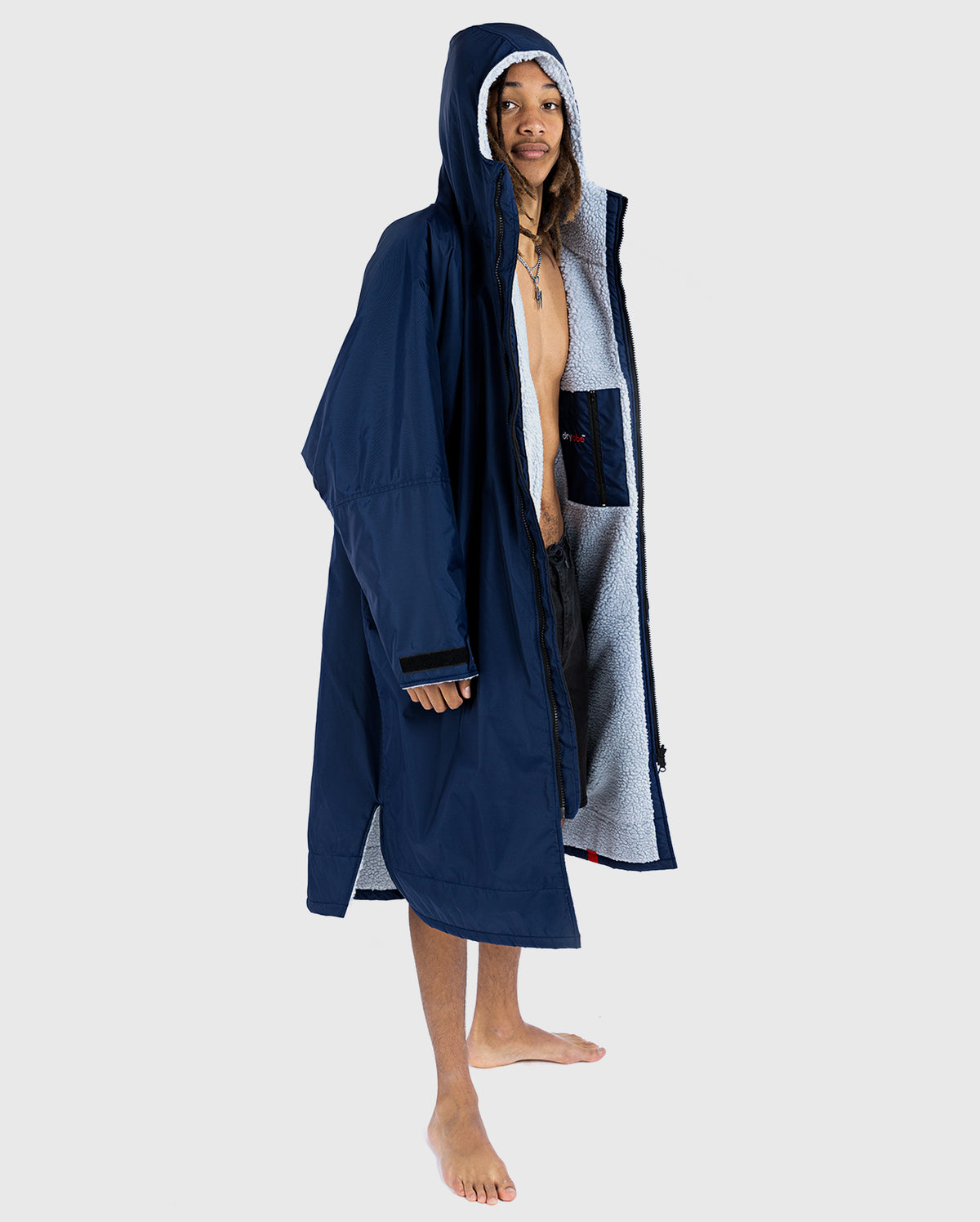 *MALE* A person standing wearing a navy dryrobe Advance with long sleeves, hood up, displaying the waterproof outer layer.