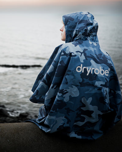 *MALE* sat on wall facing away from camera, wearing  Blue Camo dryrobe® Waterproof Poncho 