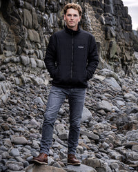 Man stood on a rocky beach wearing dryrobe® Mid-Layer Jacket