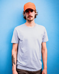 *MALE*  Man leaning against a blue wall looking into camera, wearing orange dryrobe Quick Dry Cap