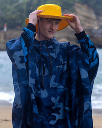 *MALE* Man wearing dryrobe Quick Dry Brimmed Hat and dryrobe® Waterproof Poncho, in the rain on the beach 