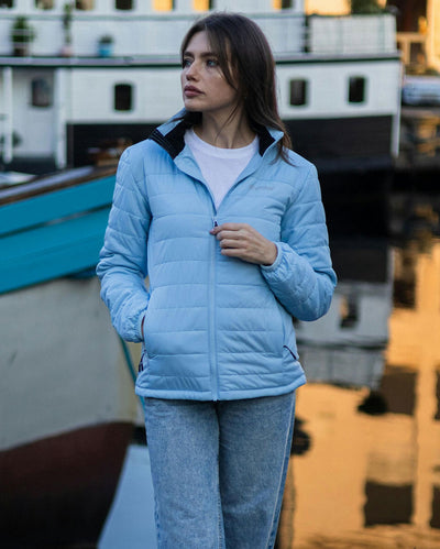 Woman stood in front of boat, wearing dryrobe Mid-layer Jacket in Ice Blue