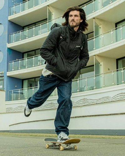 Man skating along a road, wearing dryrobe Mid-Layer Jacket in Black