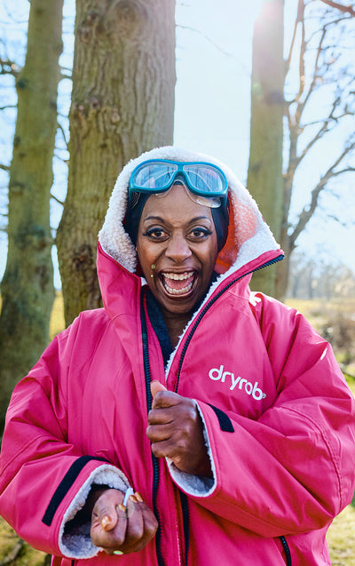 Person wearing a pink dryrobe jacket outdoors with trees in the background