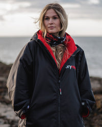 Woman on beach wearing Black Red dryrobe® Advance and dryrobe® Wrag as neck tube 