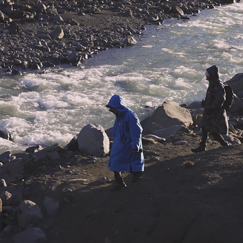 Two people walking alongside a river, wearing dryrobe® Advance