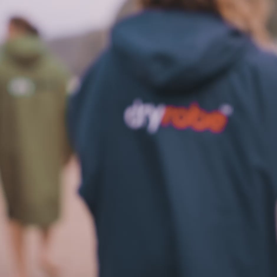 Group of adults walking across a beach, in swimming gear and dryrobe® Advance’s 