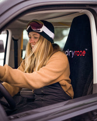 1|Woman wearing skiing attire sat in a car, using a Black dryrobe® Water-repellent Car Seat Cover