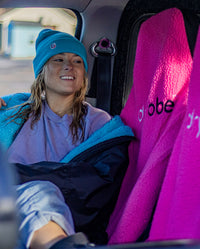 1|Woman sitting in a car with legs across seats, on Pink dryrobe® Water-repellent Car Seat Covers