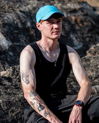 1|Man sat on rocks in the sun, wearing blue dyrobe® quick dry cap 