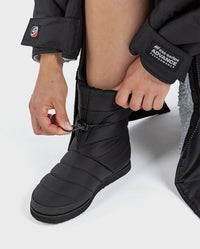 1|Person crouched down, adjusting the ankle cord of dryrobe® Eco Thermal Boots