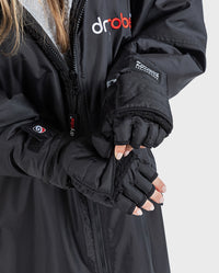 1|Woman wearing dryrobe® Eco Thermal Gloves, with both mitten flaps folded back