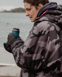 1|dryrobe® Ambassador Kerri-anne Payne stood by the sea holding a flask, wearing dryrobe® Eco Thermal Gloves